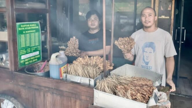 
					Kurdiawan (kaus hitam) bersama Heru (kaus putih), di gerobak Sate Pertok Pondok Indah. Sate ayam legenda ini dirintis sejak tahun 1982. (Foto: SWARAJOMBANG.com/ Khristina Kencana)
