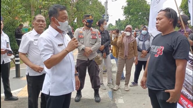 
					Sekdakab Jombang, Agus Purnomo (hem putih memegang mikropon) saat menemui [endemo LSM Genah di depan kantor Pemkab Jombang, Rabu (16/11/2022). )Foto: SWARAJOMBANG.com/ Wibisono).