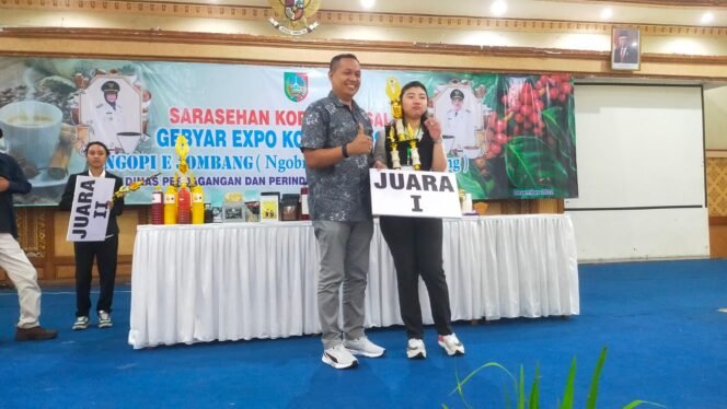 
					Kepala Bidang (Kabid) Pengembangan dan Distribusi, Wiku Birawa Filipe Dias Quintas menyerahkan hadiah barista asal Sidoarjo, Istaar Phoenix Hartanto sebagai Juara I Excelsa Signature Competition 2022. (Foto: Dok. Disdagrin Jombang).