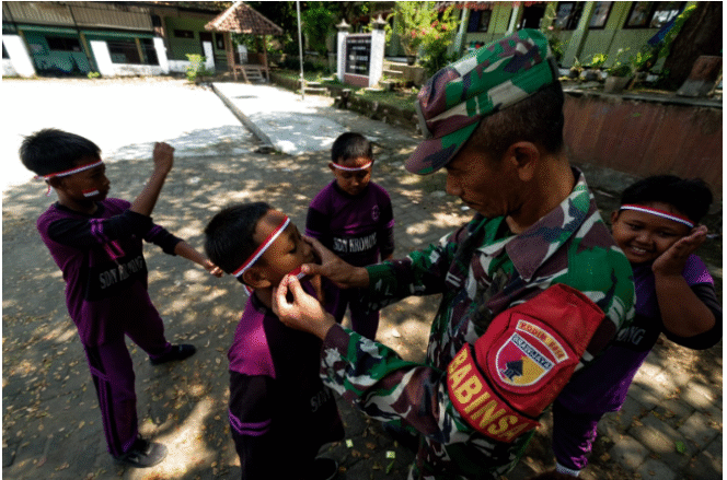 
					Babinsa menempelkan stiker merah putih di pipi anak-anak- desa  siswa SDN Kromong, kecamatan Ngusikan, lokasi TMMD 125 Jombang 2015,  jelang persiapan lomba-lomba Agustusan. Foto: Diskominfo Jombang