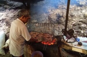 Seorang pria sedang melakukan pengasapan ikan yang selanjutnya akan menjadi menu kuliner ikan bakar di Pantai Serang, Kabupaten Blitar. (Foto:RRI Malang/Ninda Alivia)