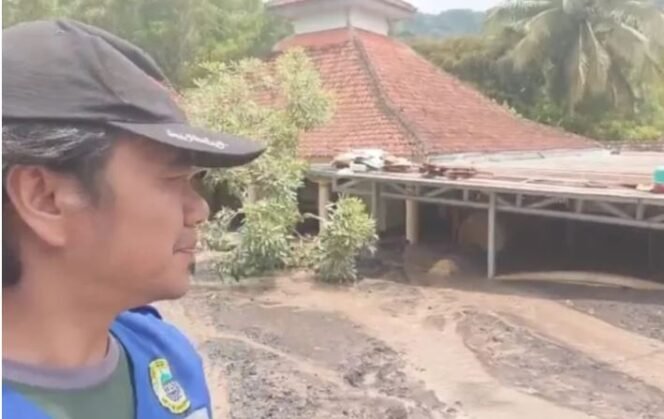 
					Warga menunjukkan sebuah masjid di Dusun Sumberlangsep yang terlihat sebagian atapnya karena diterjang banjir lahar Semeru pada Minggu (7/12/2025). Foto: Antara)