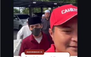Lora UF mengenakan masker dan songkok hitam, serta kemeja lengan pendek merah maroon diantar oleh beberapa orang, mendatangi Polres Bangkalan. Ia disebut sebagai terlapor kasus pencabulan dan pelecehan 15 santriwati di sebuah Pospes Bangkala. Foto: tangkap layar video Instagram@madurabagus.id