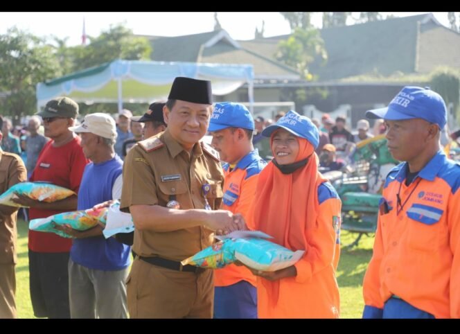 
					Sekda Jombang, Agus Purnomo menyerahkan bantuan berupa uang tunai Rp100.000 dan 5 kh beras, dibagikan kepada 2.495 warga di lapangan upcara pemkab, Senin 16 Maret 2026. Foto: diskominfo pemkab jombang