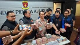 Wagiyo Santoso Aspidsus Kejati Jatim menunjukkan uang yang diamankan dari kantor dan rumah ketiga tersangka yang terlibat dalam kasus dugaan pungutan liar di lingkungan Dinas ESDM Jatim. Foto: Akira suarasurabaya.net 