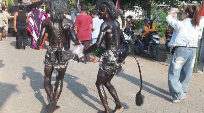 Kakan beradik Tarsipan dan Sinto mengecat tubuhnya dengan semir sepatu, turut serta memeriahkan  pawai suguh dusun di desa Plumbon Gambang, kecamatan Gudo, Jombang, Sabtu 4 Juli 2026. Foto: swarajombang.com/ ipong dwicahyono